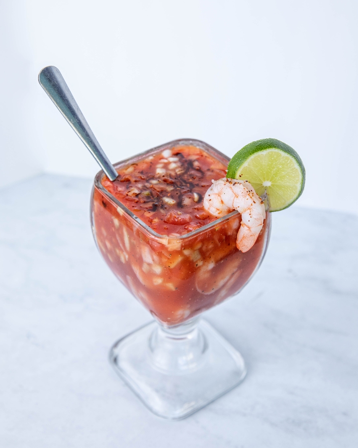 A shrimp cocktail in a cold tomato broth with a lime wheel.