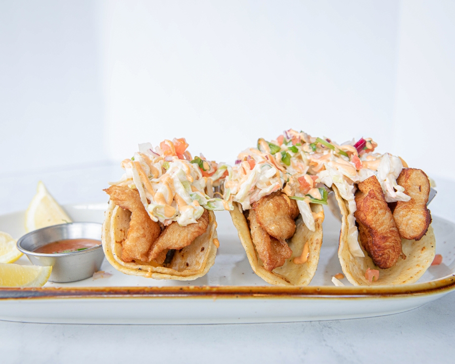 Three crispy beer-battered fish tacos topped with slaw and chipotle crema.